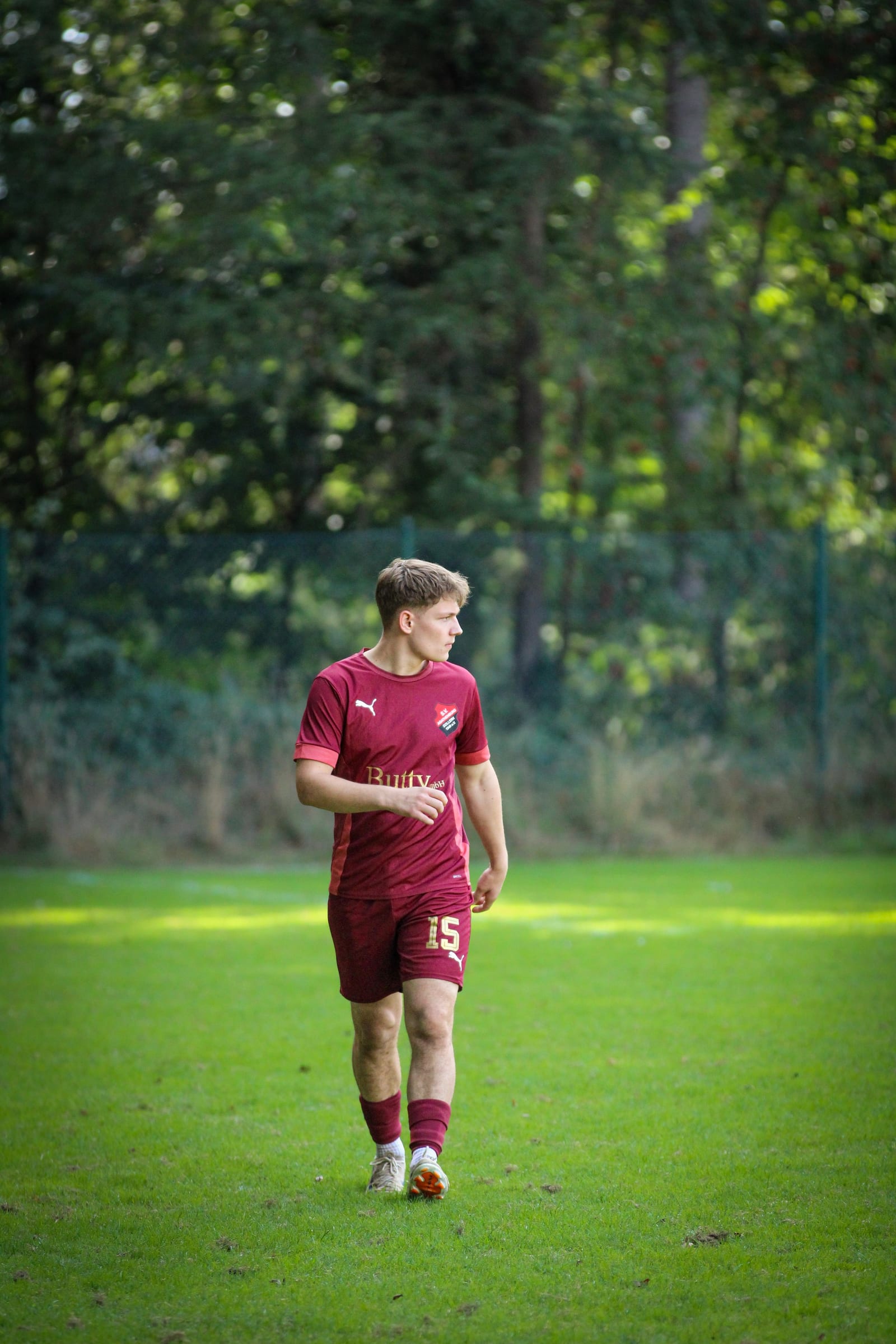 Spieler im rot-schwarzen Trikot schießt den Ball im vollen Lauf