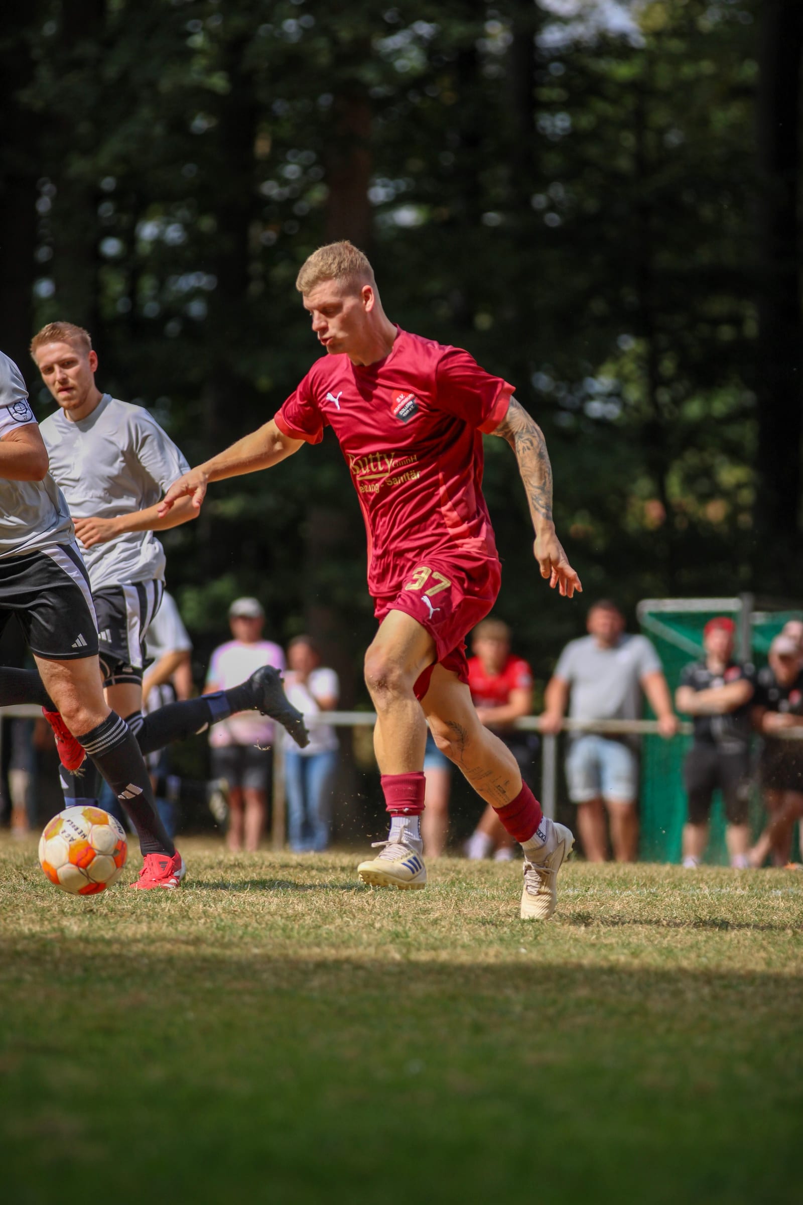 Torwart springt beim Turnier hoch und fängt den Ball über dem Kopf, davor ein Gegenspieler im grünen Trikot